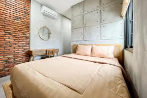 1 dormitorio con cama y pared de ladrillo en Rattanhaus R Signature Mitra RedDoorz en Palembang