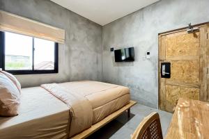 1 dormitorio con 1 cama y puerta de madera en Rattanhaus R Signature Mitra RedDoorz en Palembang
