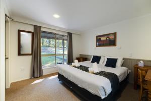 um quarto de hotel com uma cama grande e uma janela em Jindalee Spa Lodge em Vacy