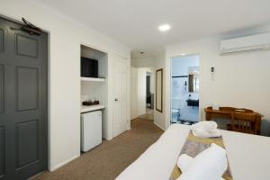 a white bedroom with a bed and a kitchen at Jindalee Spa Lodge in Vacy