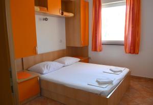 een kleine slaapkamer met een bed met oranje muren en een raam bij Apartment Gradac 13681d in Gradac