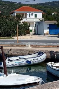 two boats are docked in the water near a house at Seaside holiday house Vinisce, Trogir - 14704 in Vinišće