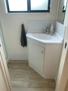 a bathroom with a white sink and a window at Beach Cottage - Port Arthur in Port Arthur