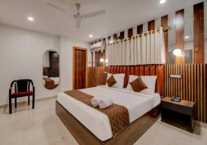 a bedroom with a large bed and a red chair at Hotel Sai Rain Tree in Guwahati