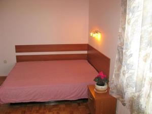 ein kleines Schlafzimmer mit einem Bett mit rosa Bettwäsche und einer Pflanze in der Unterkunft Apartments with a parking space Sukosan, Zadar - 14742 in Sukošan