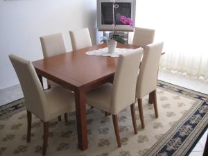 a dining room table with white chairs and a television at Apartments with a parking space Zadar - Diklo, Zadar - 14750 in Zadar