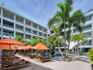 a hotel with chairs and umbrellas and a pool at The Kee Resort & Spa in Patong Beach