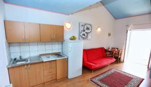 a kitchen with a red couch in a room at Apartments and rooms by the sea Stanici, Omis - 14783 in Omiš