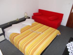 a bedroom with a bed and a red couch at Apartments for families with children Pasman - 14788 in Mali Pašman