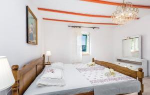 2 bedden in een witte kamer met een kroonluchter bij Holiday house with a parking space Supetarska Draga - Gornja, Rab - 14775 in Rab