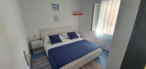 sypialnia z niebiesko-białym łóżkiem i oknem w obiekcie Family friendly seaside apartments Sevid, Trogir - 14790 w Marinie