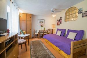 a bedroom with a purple bed and a tv at Apartments by the sea Vrbnik, Krk - 14806 in Vrbnik