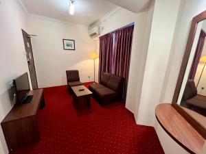 a living room with a couch and a chair in a hotel room at Hotel Yt Midtown Kuala Terengganu in Kuala Terengganu