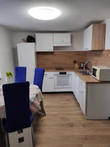 a kitchen with white cabinets and a table with blue chairs at Apartments with a parking space Smrika, Kraljevica - 14812 in Šmrika