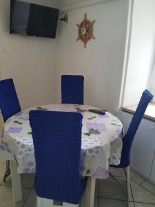 a dining room table with blue chairs and a table and a clock at Apartments with a parking space Smrika, Kraljevica - 14812 in Šmrika