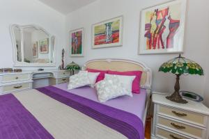 a bedroom with a purple bed and a mirror at Apartment Arbanija 14825b in Trogir
