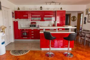 a red kitchen with red cabinets and black chairs at Apartment Arbanija 14825b in Trogir