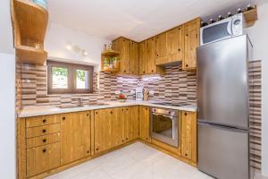 a kitchen with wooden cabinets and a stainless steel refrigerator at Holiday house with a parking space Risika, Krk - 14860 in Vrbnik