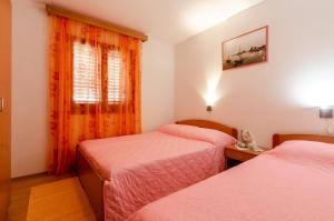 1 Schlafzimmer mit 2 Betten und einem Fenster mit orangefarbenen Vorhängen in der Unterkunft Seaside holiday house Karbuni, Korcula - 14889 in Prizba