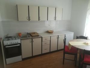 a kitchen with white cabinets and a stove and a table at Apartments with a parking space Zagreb - 14890 in Zagreb