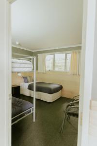 a room with two bunk beds and a chair at Waitomo Village Chalets home of Kiwipaka in Waitomo Caves