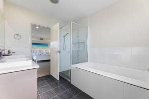 a white bathroom with a bath tub and a sink at Kianga Breeze in Kianga +18 photos