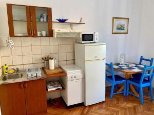 a small kitchen with a white refrigerator and a table at Apartments and rooms by the sea Opatija - 14937 in Opatija