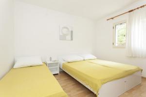 two beds in a room with white walls and a window at Apartments by the sea Stomorska, Solta - 14960 in Stomorska