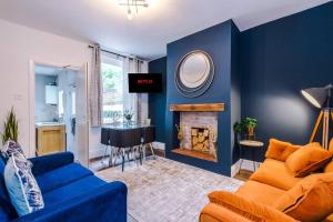 Charming 3 Bed Home in the Garden Quarter, Chester في تشيستر: غرفة معيشة زرقاء مع أريكة ومدفأة