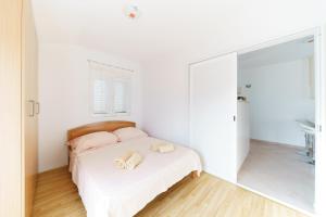 a white bedroom with a bed and a mirror at Apartments by the sea Preko, Ugljan - 14985 in Preko