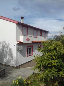 une maison blanche avec des fenêtres rouges sur son côté dans l'établissement Apartments with a parking space Poljana, Ugljan - 15019, à Poljana