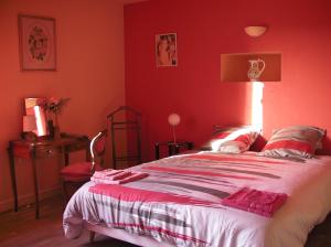 - une chambre avec des murs rouges et un grand lit dans l'établissement Le Clos Crista Galli, à Saint-Junien