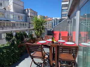 uma mesa de madeira e cadeiras numa varanda do apartamento em Penthouse with terrace and views near Oza's beach em La Coruña