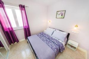 una camera da letto con un letto con tende viola e una finestra di Apartments with parking space Zaton, Zadar - 15000 a Zaton