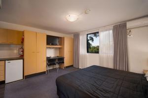 a hotel room with a bed and a desk and a kitchen at Drummoyne Furnished Apartments in Sydney