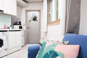 a small apartment with a blue couch and a laundry room at Sweet Stay in Seoul