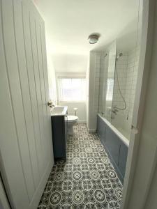 een badkamer met een bad, een wastafel en een toilet bij Cosy cottage 5 minutes walk to beach in Caister-on-Sea