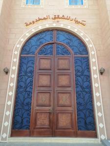 duże drewniane drzwi na boku budynku w obiekcie سيبار للشقق المخدومة Sippar Serviced Apartments w mieście Hotat bani tamim