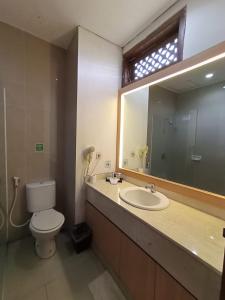 a bathroom with a toilet and a sink and a mirror at Al Azhar Azhima Hotel Resort and Convention in Solo