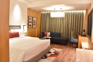 um quarto de hotel com uma cama e uma cadeira em Ramada by Wyndham Katra Station Road em Katra