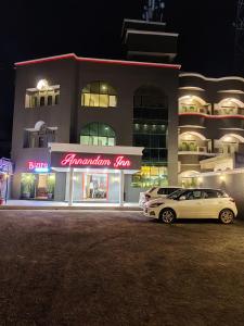 een witte auto geparkeerd voor een gebouw 's nachts bij Annandam Inn(Hotel Anand) in Seonī