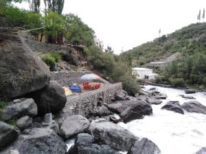 a river with some chairs and umbrellas on the rocks at Chogho-Sar Huts in Ponedas