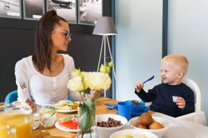 Eine Frau und ein Baby sitzen am Tisch und essen Essen. in der Unterkunft Golden Tulip Gdańsk Residence in Danzig