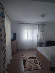 sypialnia z łóżkiem, oknem i dywanem w obiekcie Dumbrava Minunată w mieście Peşteana
