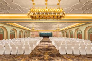 an empty hall with white chairs and a chandelier at The Hillock Ahmedabad in Ahmedabad