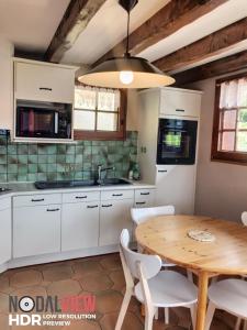 a kitchen with white cabinets and a wooden table at Chalet LA TOUPINE centre St Gervais in Saint-Gervais-les-Bains