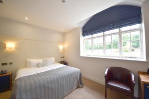 a bedroom with a bed and a window and a chair at The Elvetham Hotel in Farnborough