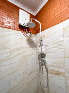 a shower with a shower head in a bathroom at Ginza Bungalow Yogyakarta in Demangan +3 photos