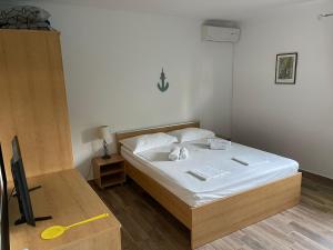 Schlafzimmer mit einem Bett mit weißer Bettwäsche und einem TV in der Unterkunft Apartments Mila - Mala Duba in Živogošće