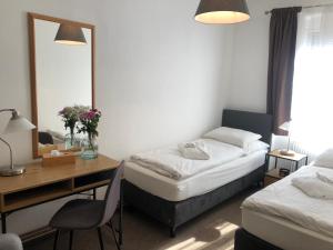 a room with two beds and a desk and a mirror at Penzion U Kašpara in Lovosice
